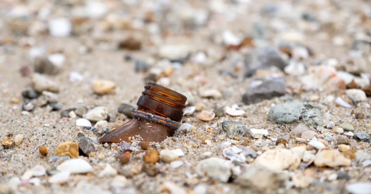 Close-up of broken glass bottles on a beach. Rage rooms by state.